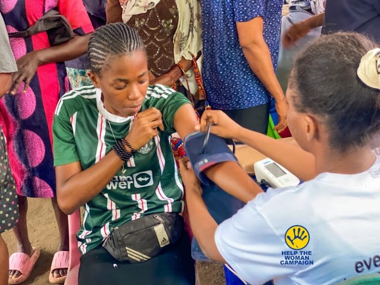 A volunteer checking a woman's blood pressure at a free medical outreach