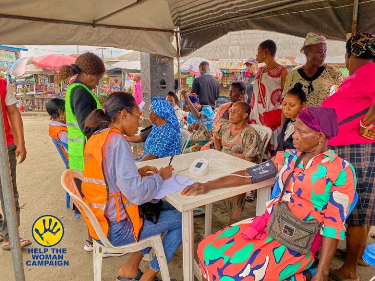 A volunteer checking a woman's blood pressure at a free medical outreach