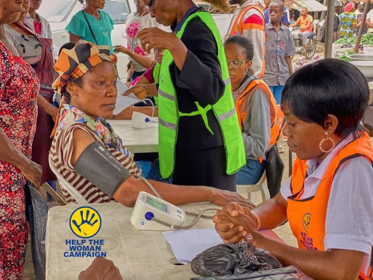 A volunteer checking a woman's blood pressure at a free medical outreach