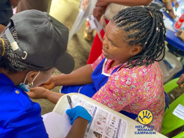 A health worker registering a woman for screening at a Help The Woman Campaign market outreach